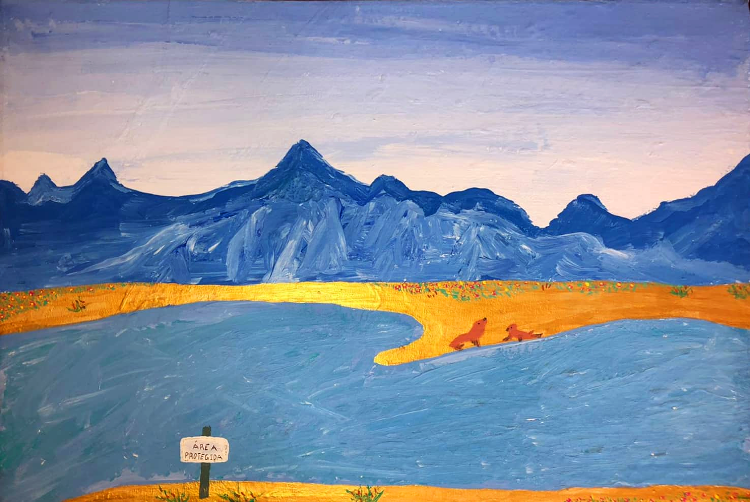 Paisaje de laguna con fondo de montañas en tonos azules en contraste con la arena dorada y un par de lobos marinos en al orilla.