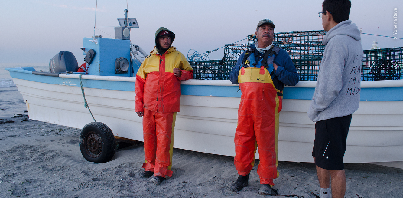 Pescadores que conversan con Pablo, con panga de fondo
