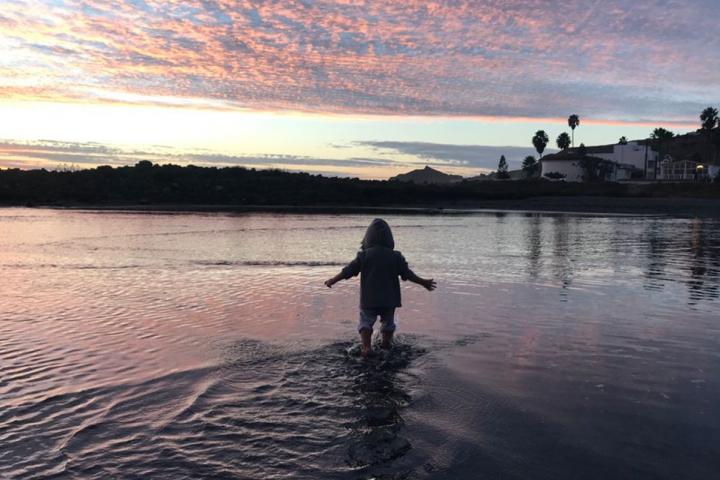 Niño a contraluz en el agua de la ensenada que se forma en San Miguel cuando sube la marea.