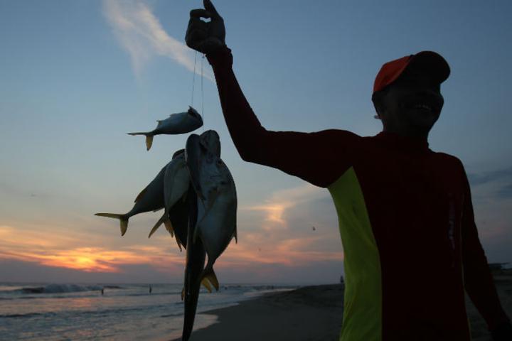 Fisherman holding fish at sunset in Sonora